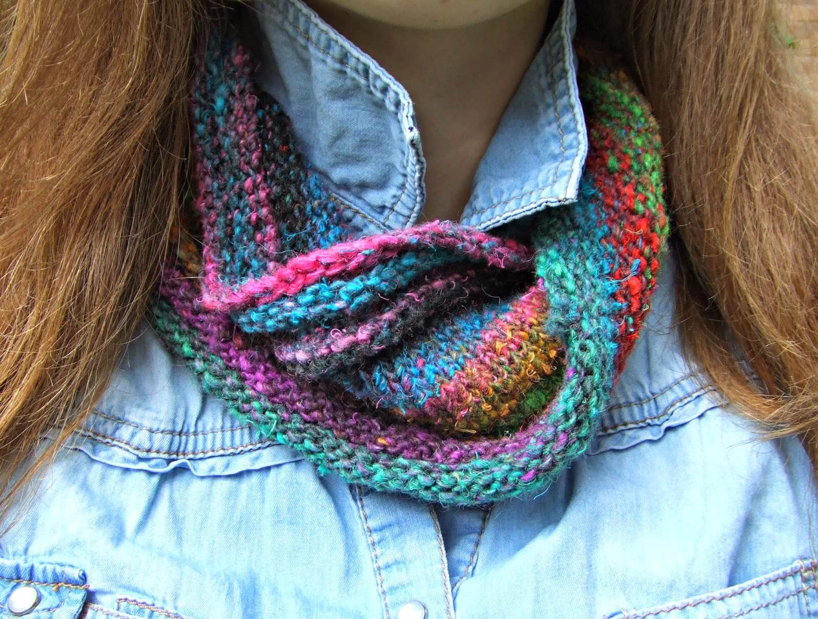 Big daughter is wearing a multi-coloured knitted cowl with a blue denim shirt