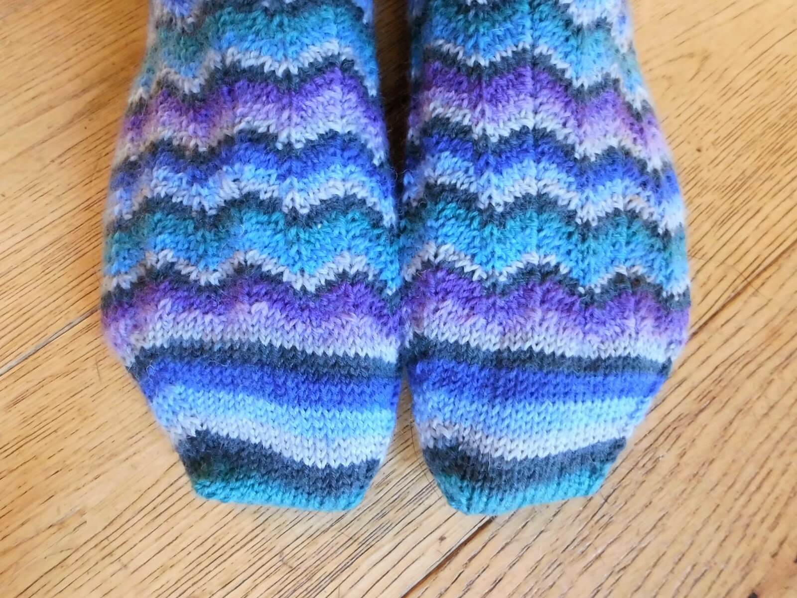 A pair of Neat Ripple Socks modelled on feet. The model is standing on a wooden floor.