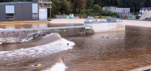 The surfing wave is half way across the photo now, the surfer is riding the wave and the beginners are still waiting!