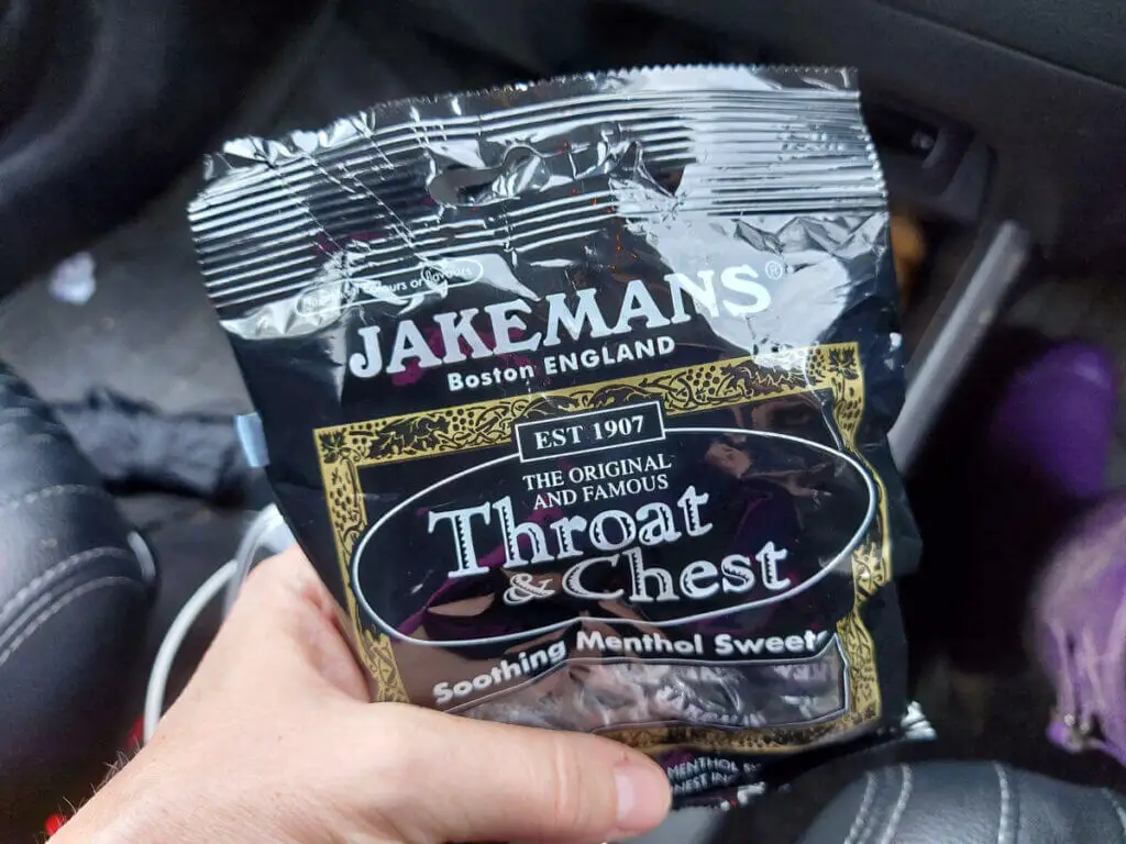 Christine is holding a black plastic packet of Jakemans cough sweets.