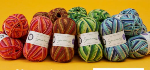 A stack of balls of Signature 4ply from the Winwick Mum Seasons range are gathered together on a mustard-coloured background.