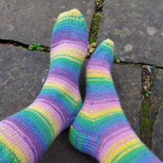 Christine is wearing her new Wildflower socks and wiggling her toes! The socks are pictured against a damp stone flag background.