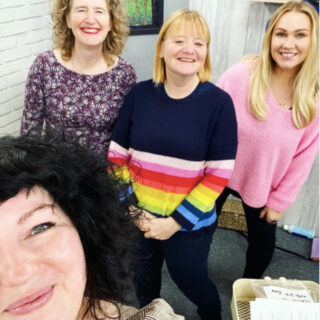 Four women are smiling at the camera in a selfie.