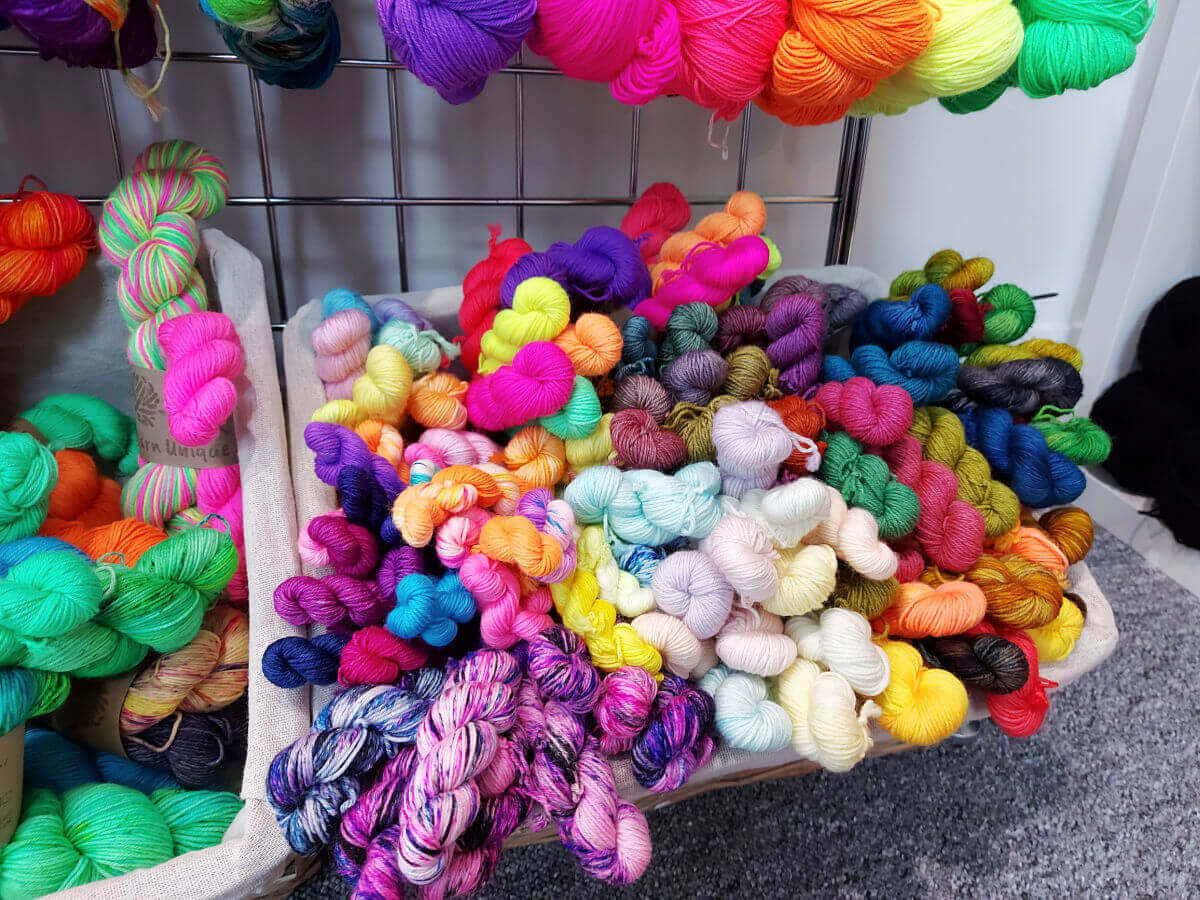 Mini skeins of brightly coloured yarn in a basket.