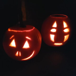 Two carved pumpkins lit up in the dark.