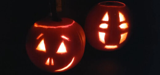 Two carved pumpkins lit up in the dark.