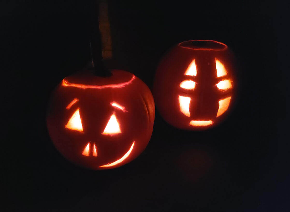 Two carved pumpkins lit up in the dark.