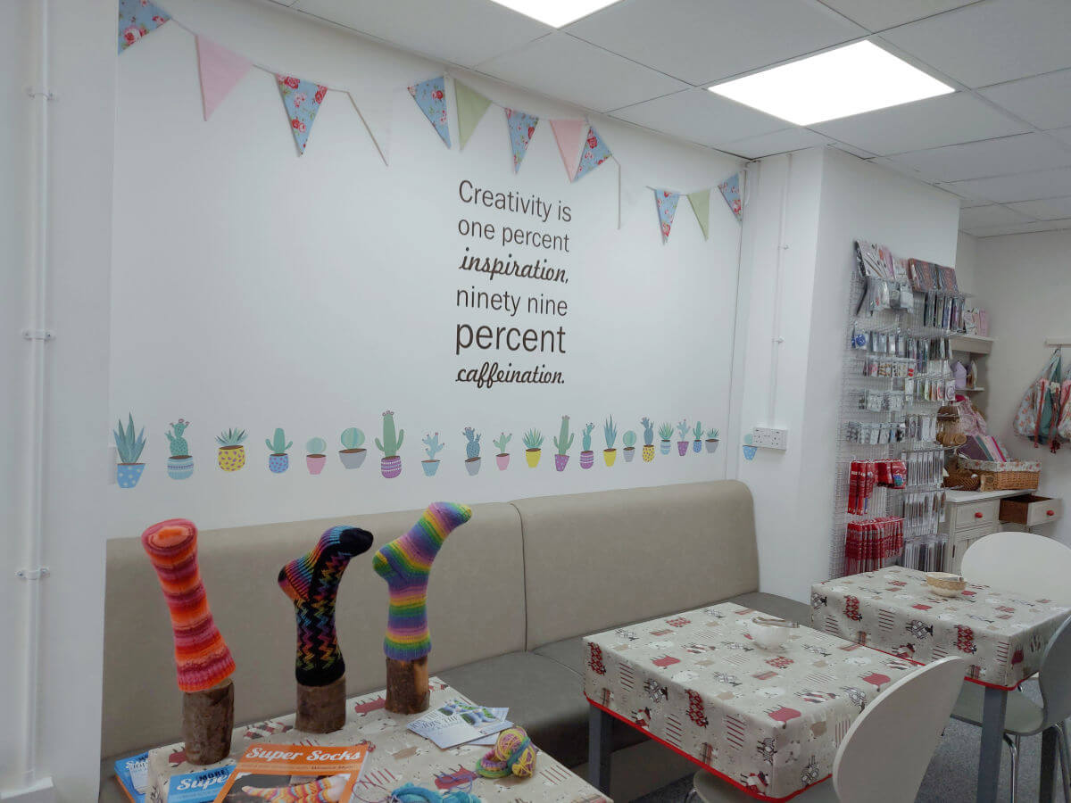A mural is on the wall above the tables and chairs. The words read 