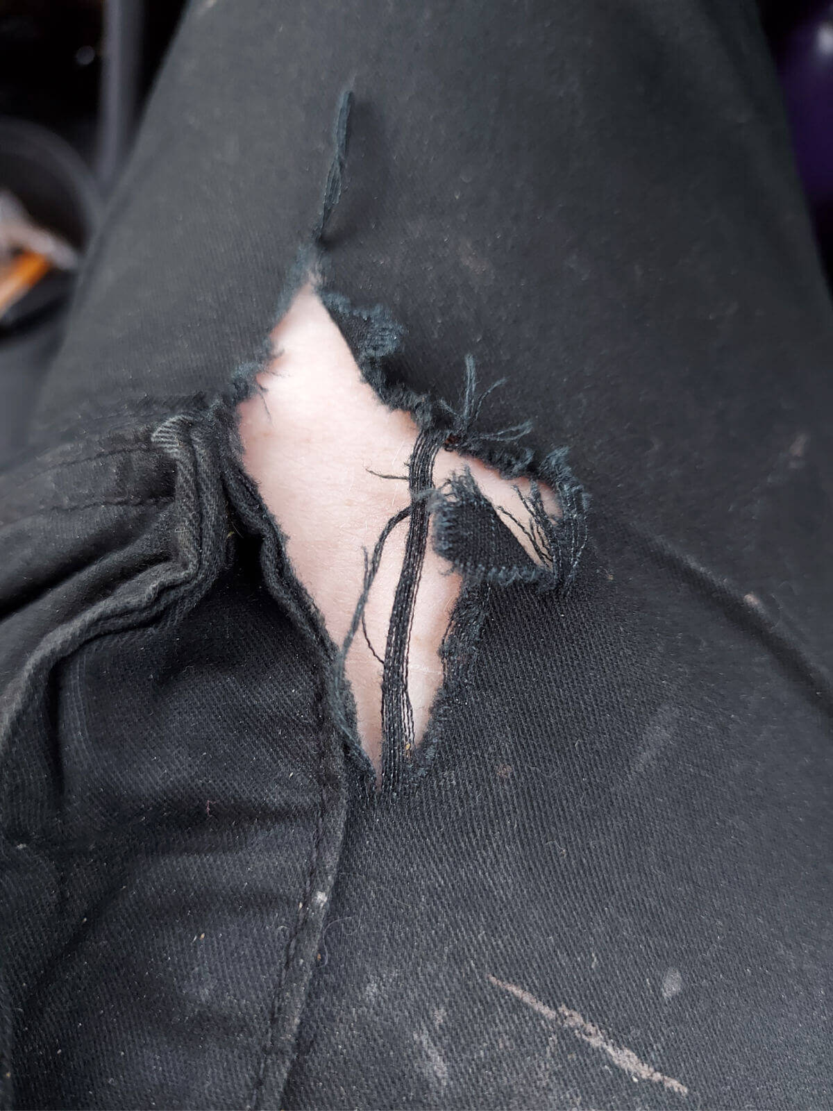A large hole in a pair of black trousers.