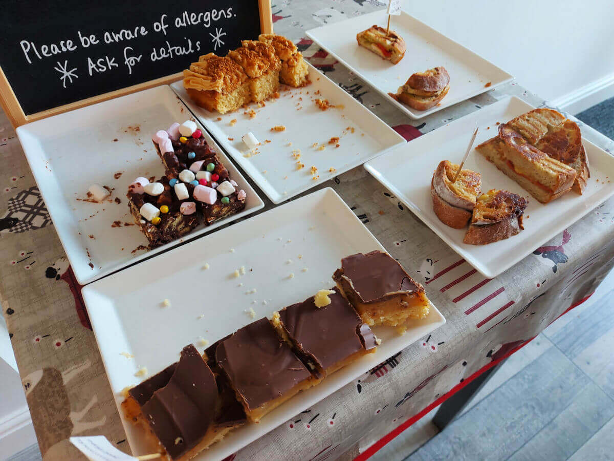 A close up of the plates and cakes on the table. There are also a lot of crumbs!