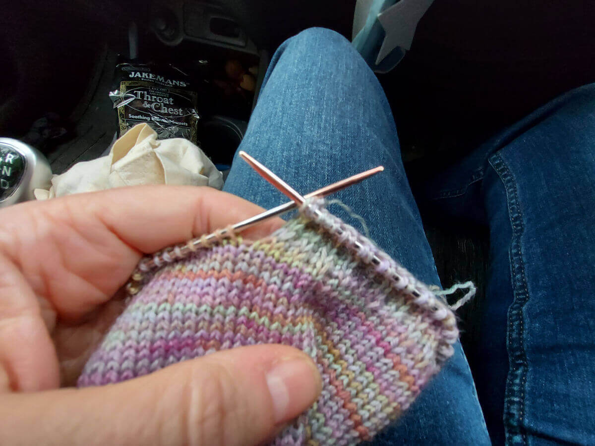 A partly-knitted sock on a short circular needle. The heel flap has been started and you can see the slip stitches in the fabric.