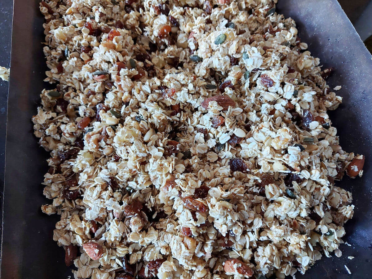 A baking tray is spread with the muesli mixture ready for the oven.