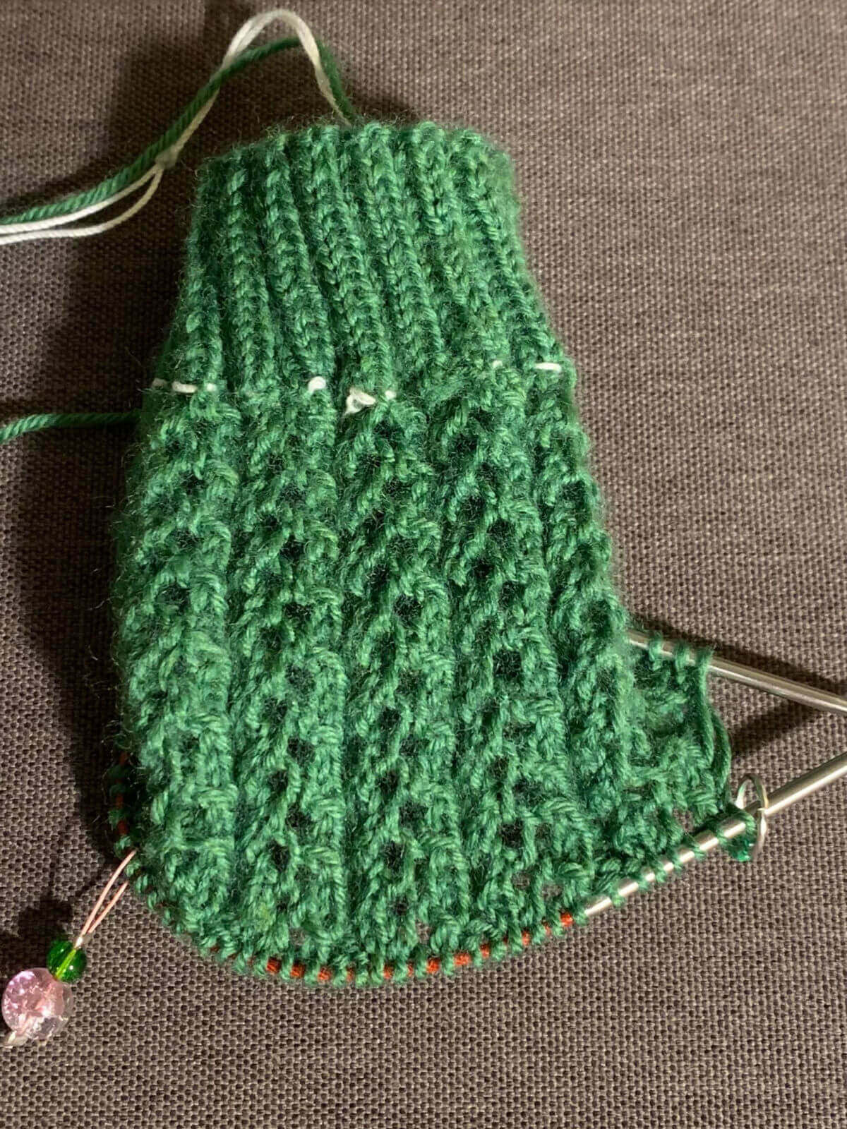 A half-knitted Easy Lace Sock in green yarn