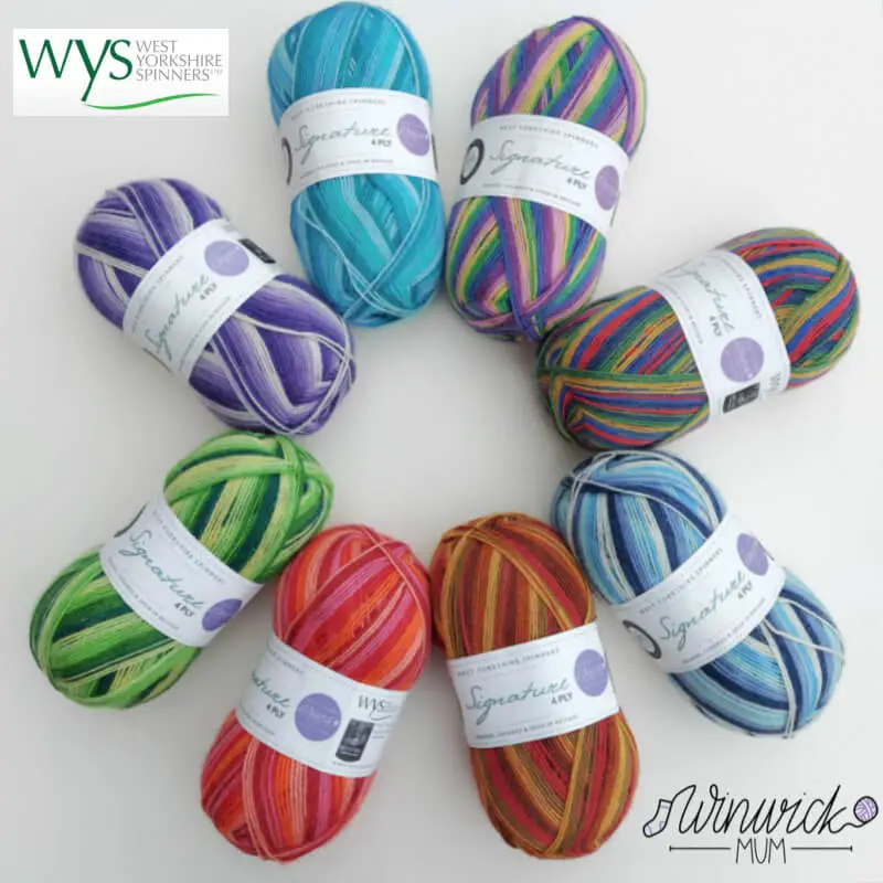 Eight balls of yarn in Winwick Mum colourways of purples, greens, blues, reds, browns and pinks are set out in a circle