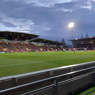 A football match is taking place in a floodlight stadium.
