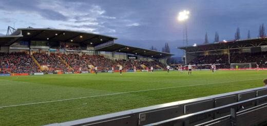 A football match is taking place in a floodlight stadium.