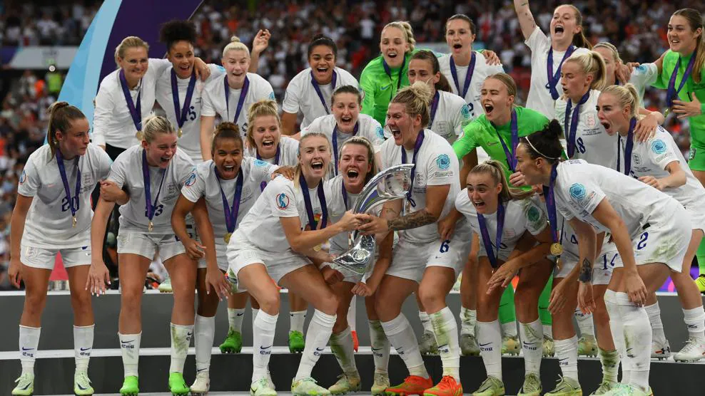 The England women's football team, all in white kit apart from the goalies in bright green, celebrate winning the Euros