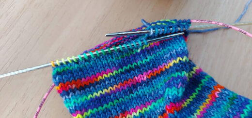A partly-knitted multicoloured sock on a long circular needle.