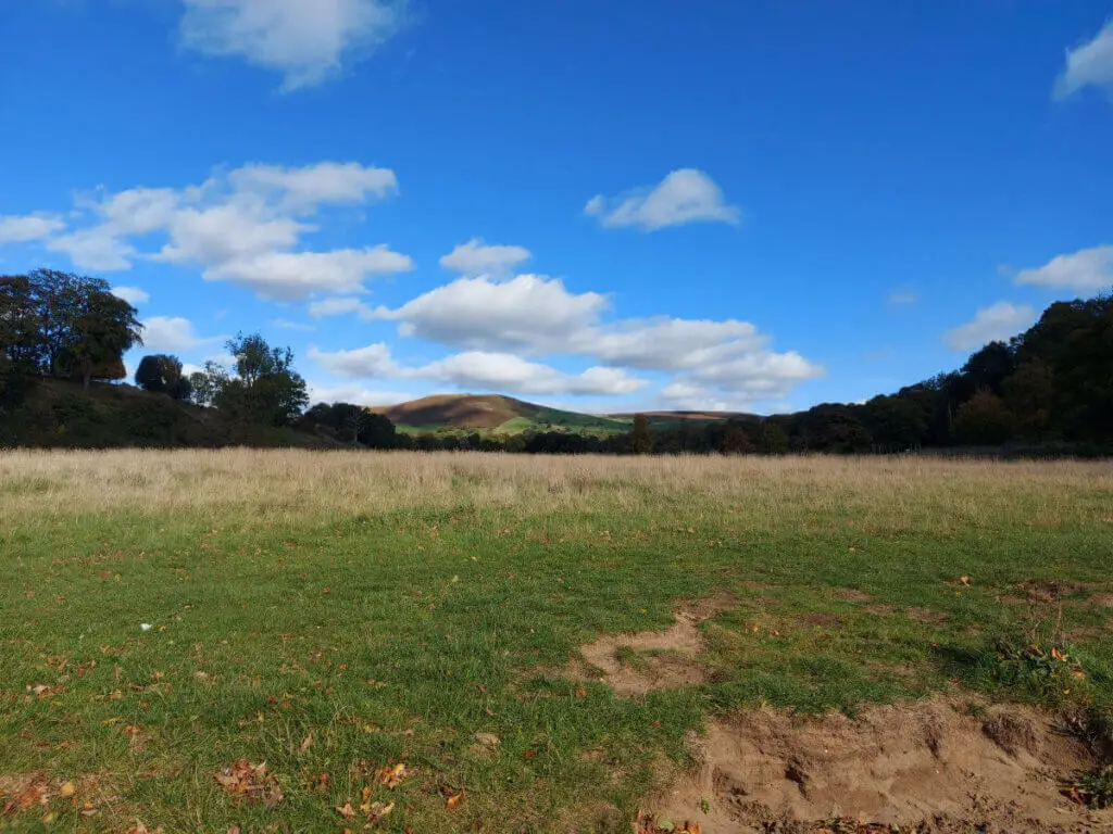A hill in the distance with shadows created by clouds