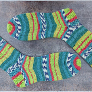 A pair of patterned socks in stripes of shades of green and red on sock blockers lying on a brown shiny tile
