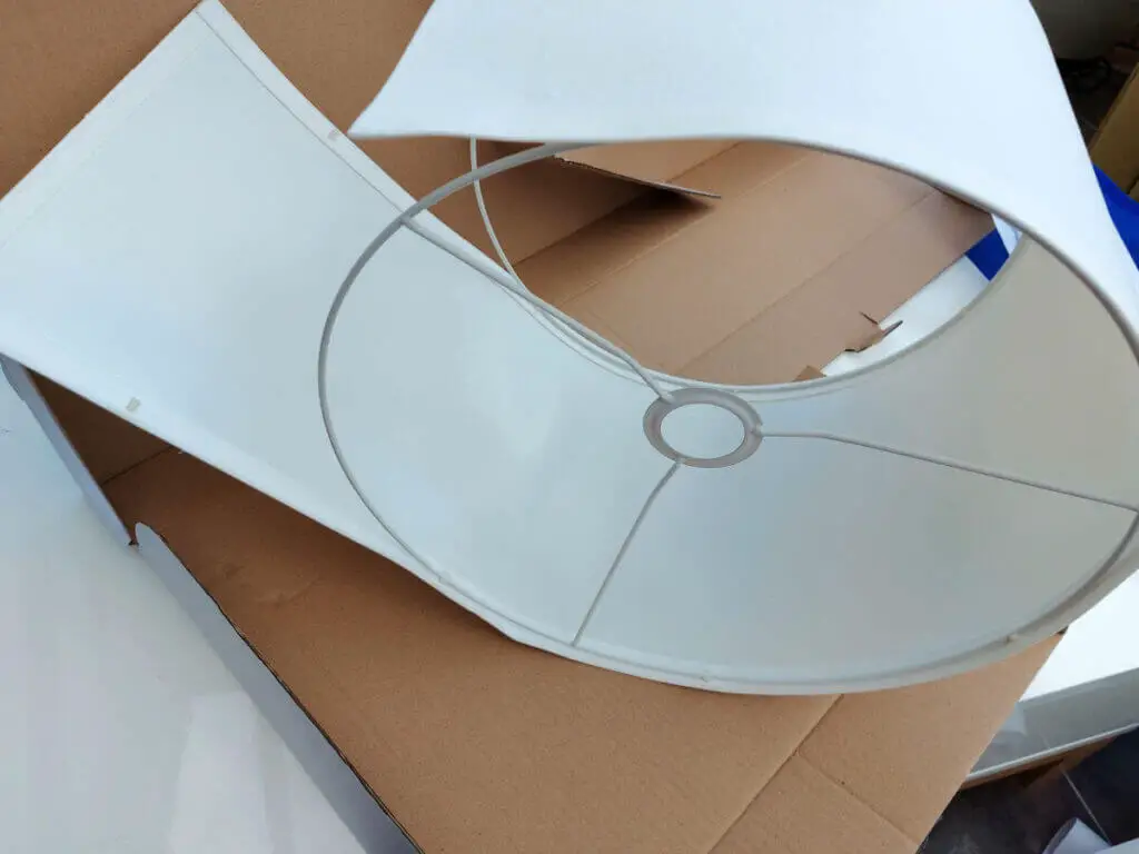 A cream lamp shade being rolled around a circular lampshade frame