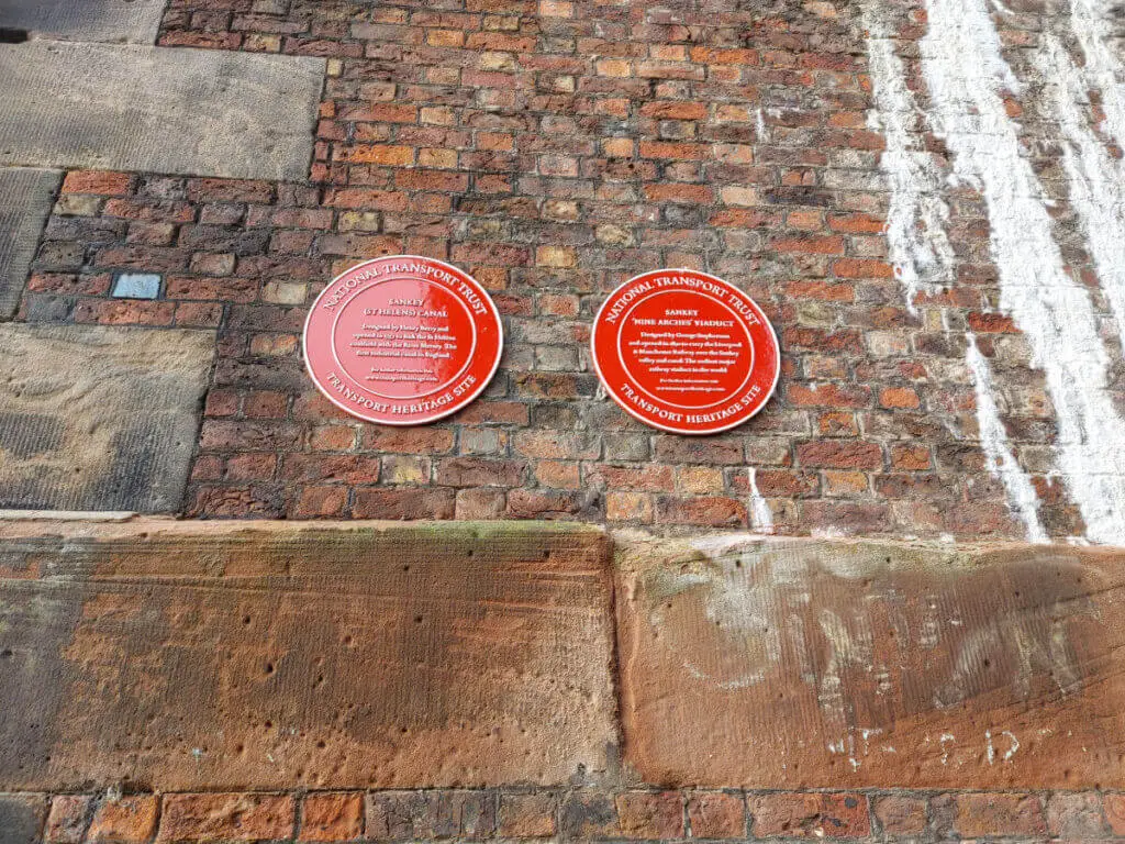 Two round red plaques attached to a brick wall