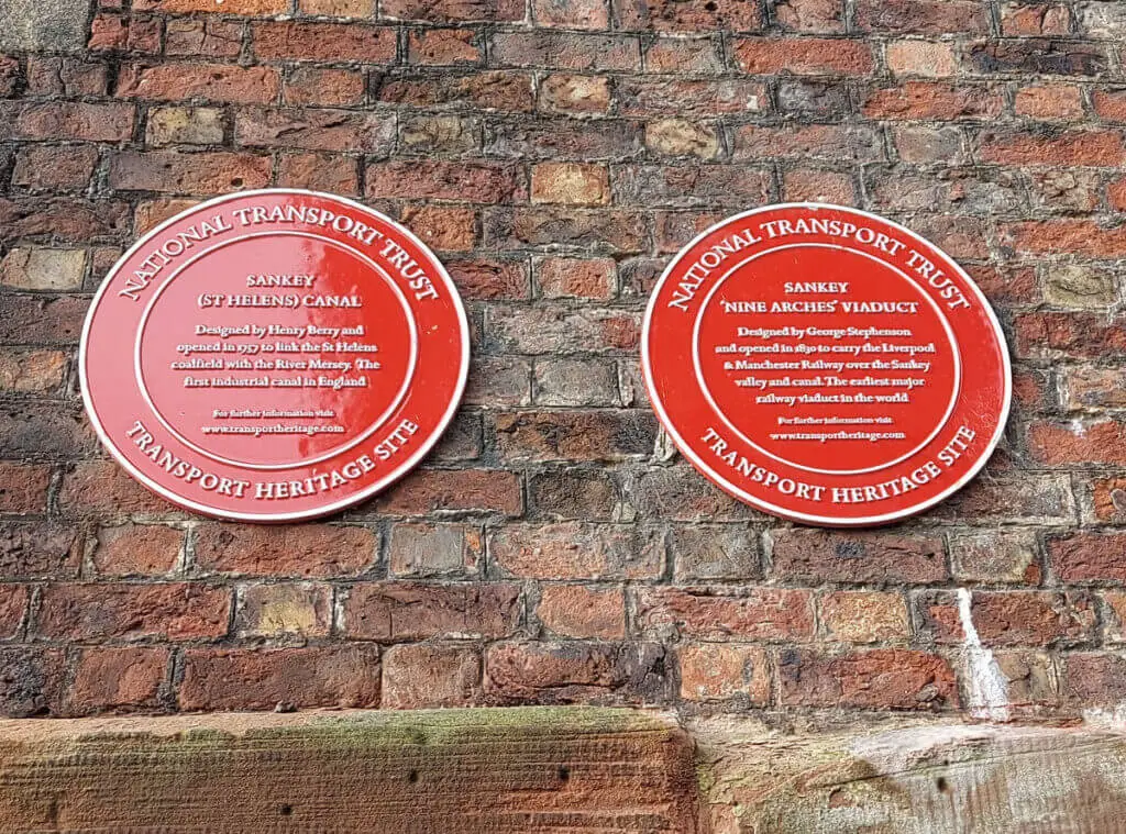A close up of two round red placques attached to a brick wall