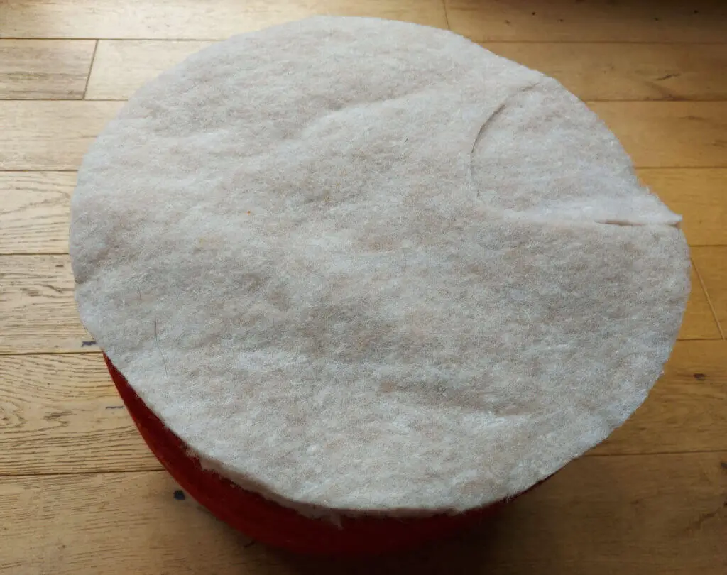 A red pouffe covered with a beige insulating fabric