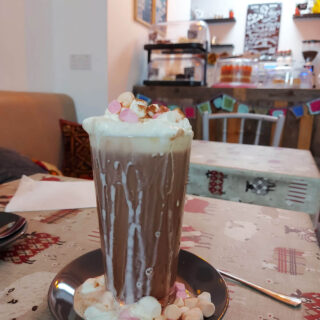 A tall glass of hot chocolate on a cafe table