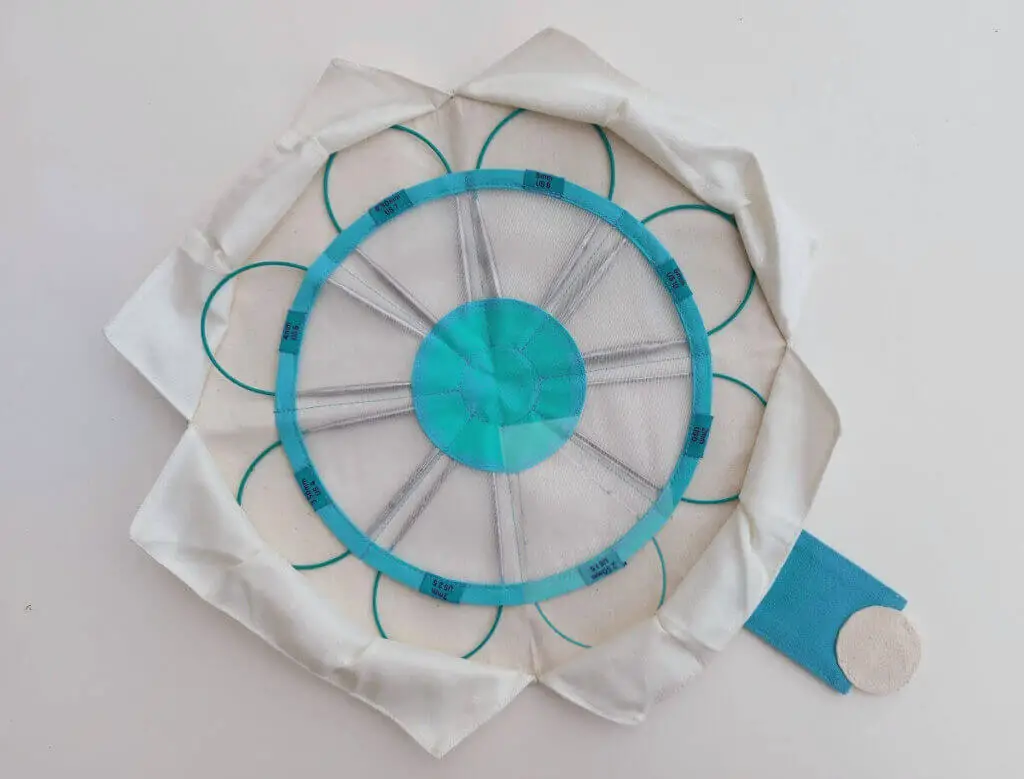A circular fabric needle case opened up to look like a flower. The needles are arranged to look like petals.