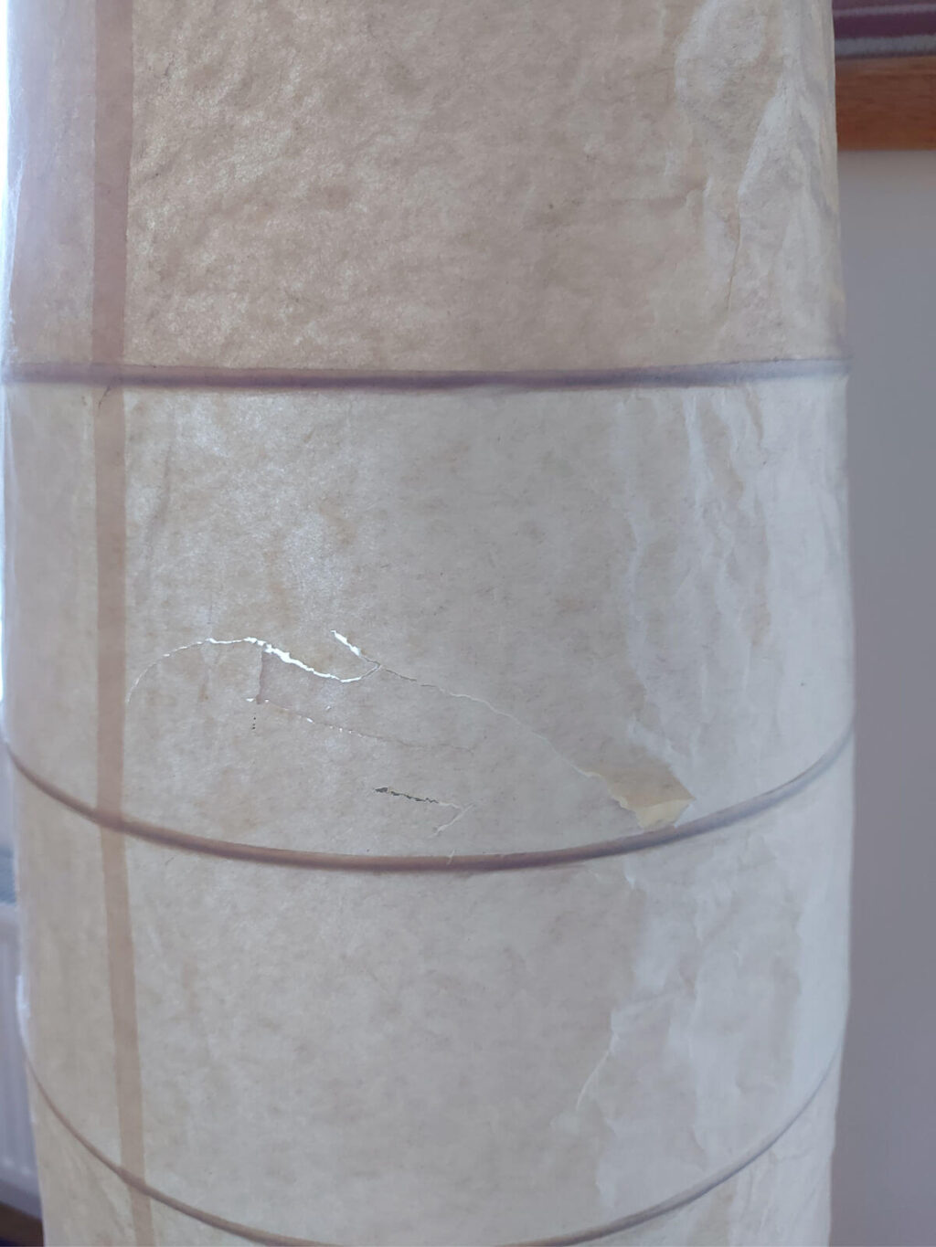 A small rip in a yellowed paper lamp shade