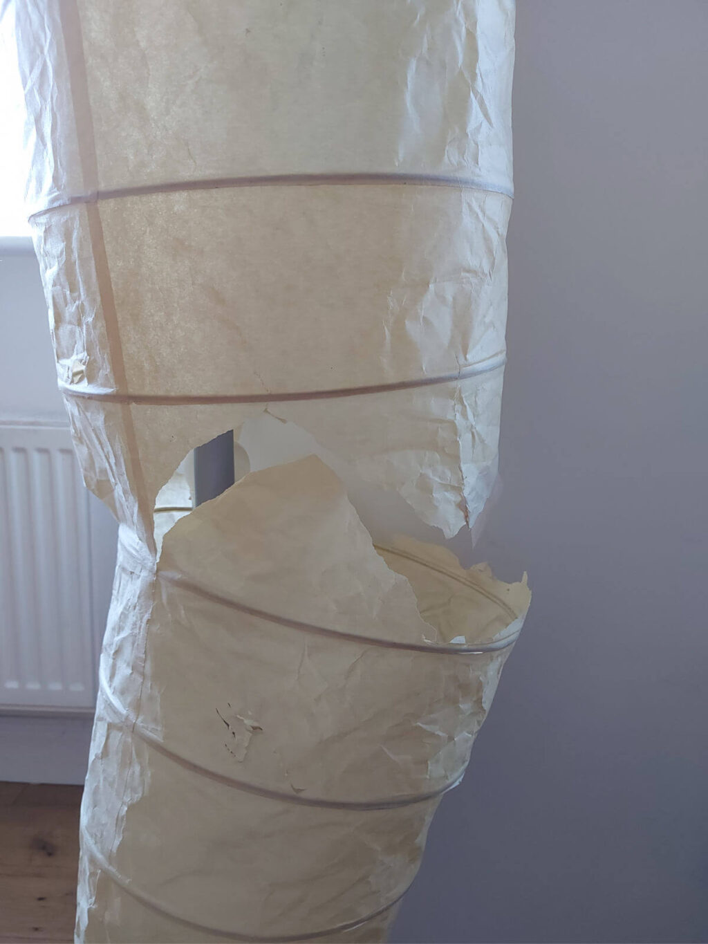 A paper lampshade which has almost ripped in half