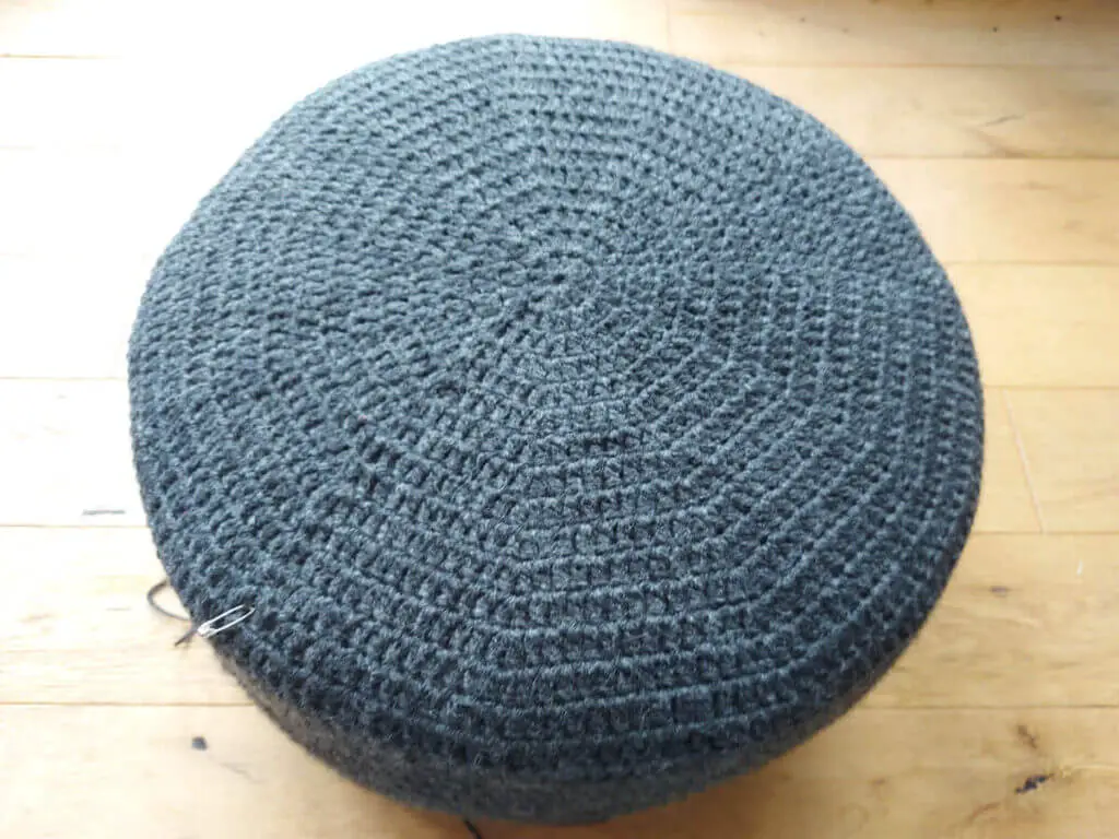 A grey crocheted cover on a pouffe