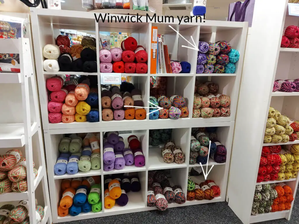 Square white shelving units in a yarn shop filled with brightly coloured yarn