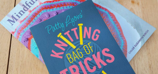 Two books - Mindful Knitting and Patty Lyons' Knitting Bag of Tricks lie on a wooden coffee table next to an orange mug of tea