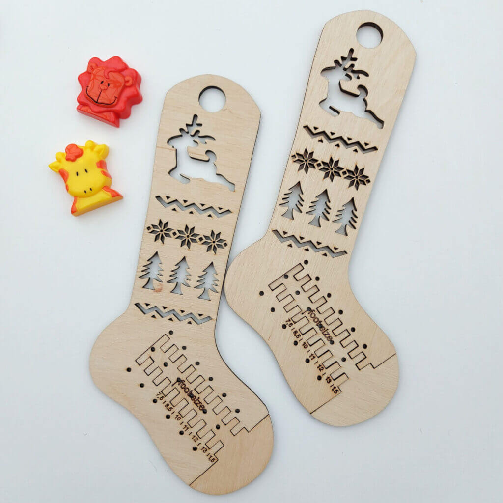 Two adjustable wooden sock blockers in children's sizes lie on a white background next to an orange lion toy and a yellow giraffe toy