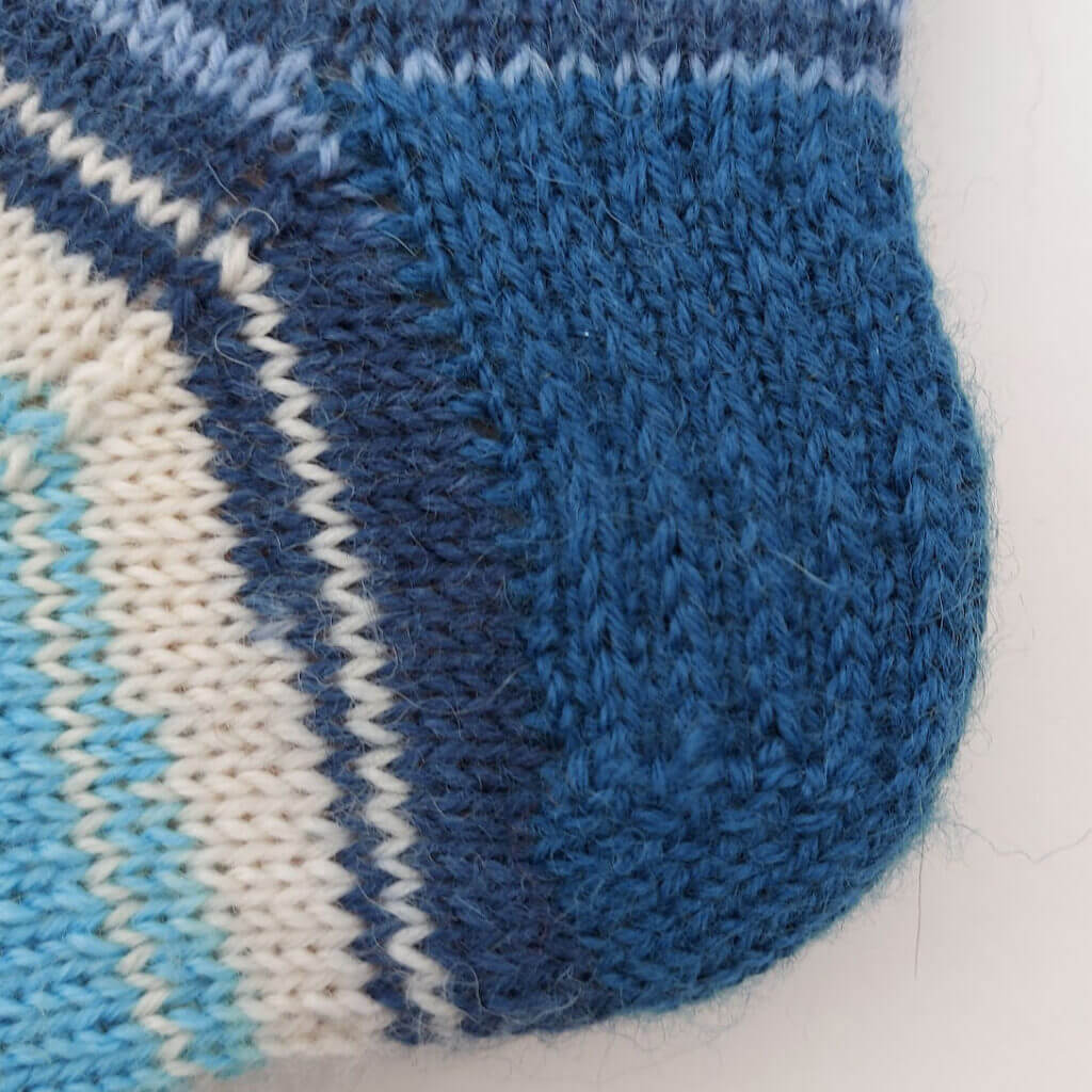 A close up of a blue heel flap knitted in heel stitch.