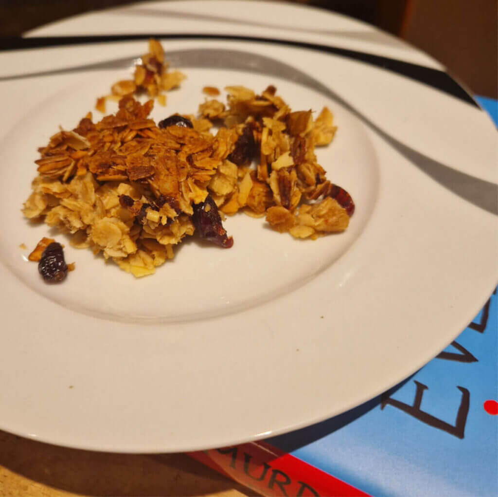 A plate of flapjack crumbs resting on a hardback book