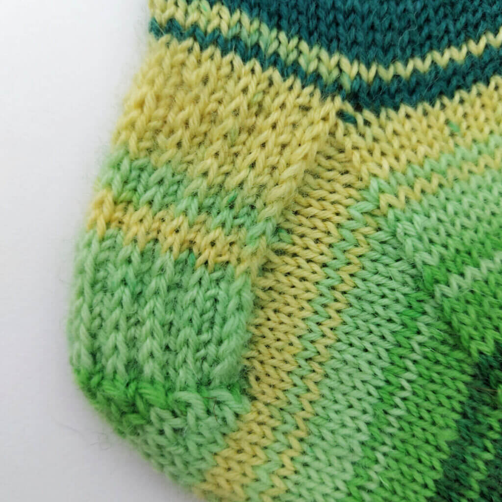 A close up of a green heel flap knitted in heel stitch.