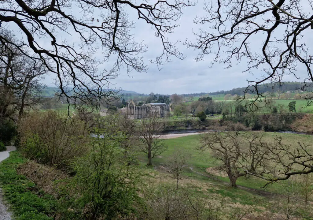 A view down a hill to the ruins of Bolton Abbey