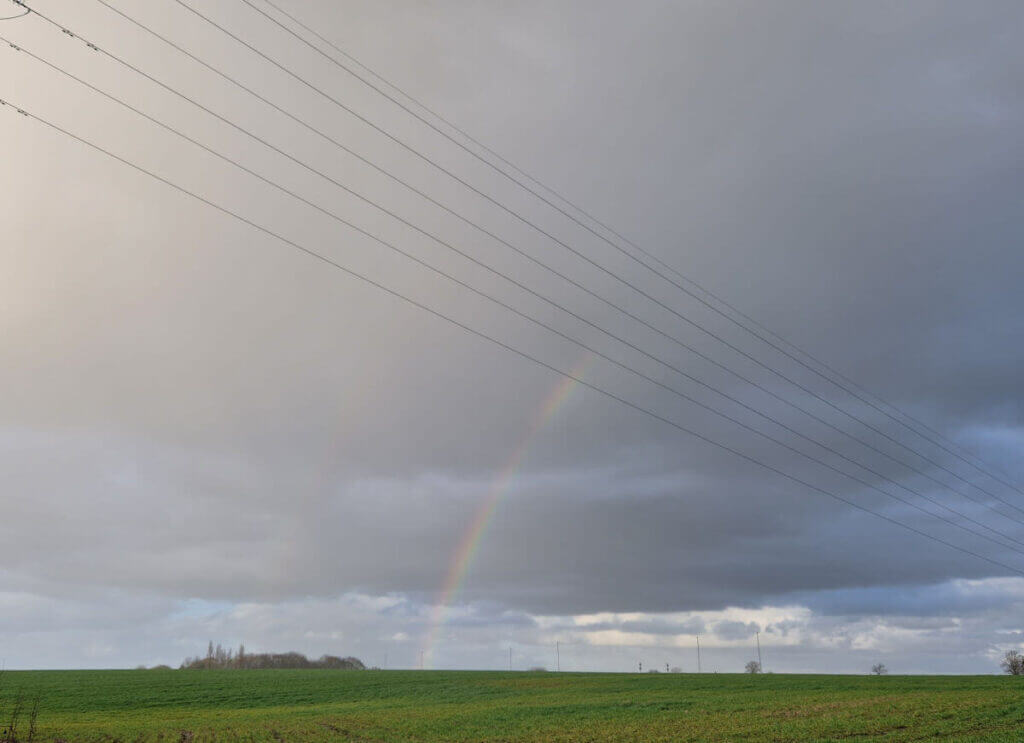 A faint double rainbow against a dark sky across a field