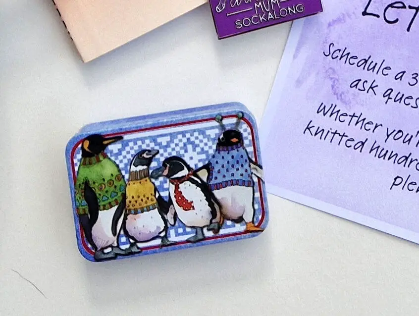 A close up of a small metal tin with a picture of penguins on it