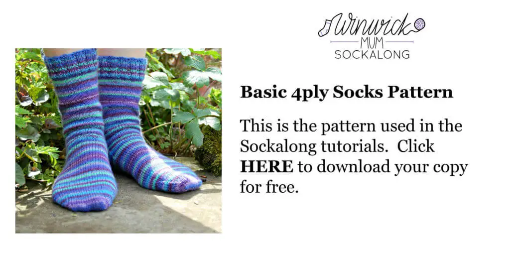 A pair of blue, green and purple striped socks modelled on feet. The model is standing on a stone slab surrounded by plants. Winwick Mum | Basic 4ply Socks