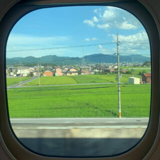 A view of Kyoto countryside through a round train window