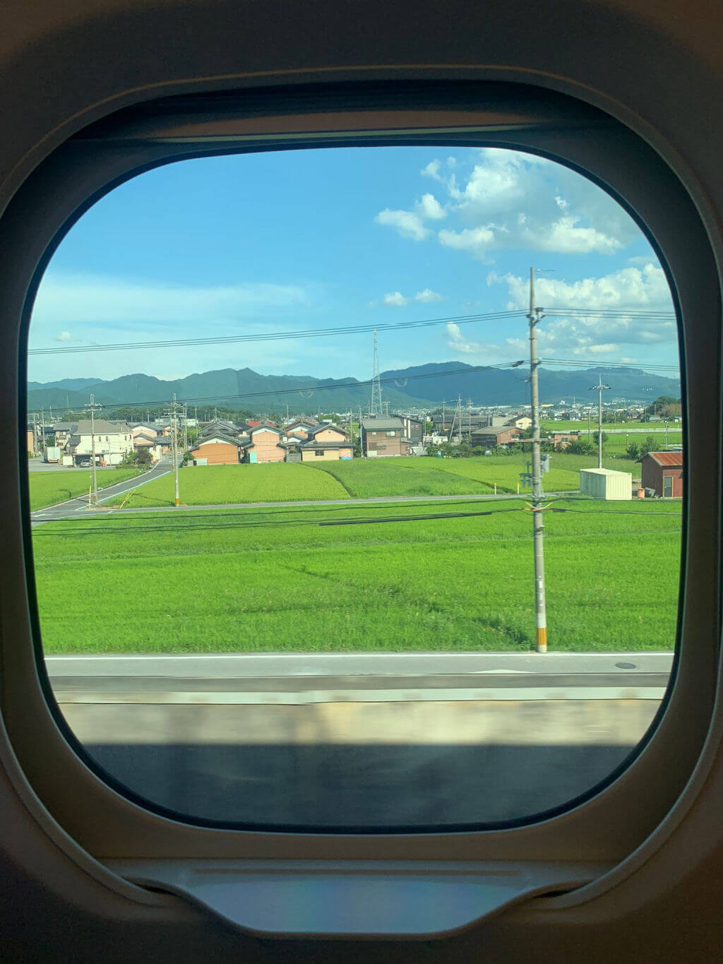 A view of Kyoto countryside through a round train window