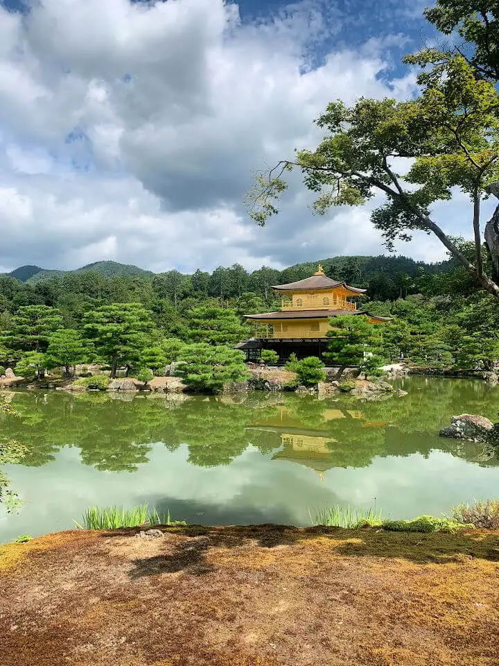 A golden temple in the distance across a green lake