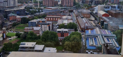 A view across Manchester from the cocktail bar of a tall hotel building. There is a cocktail menu on the table