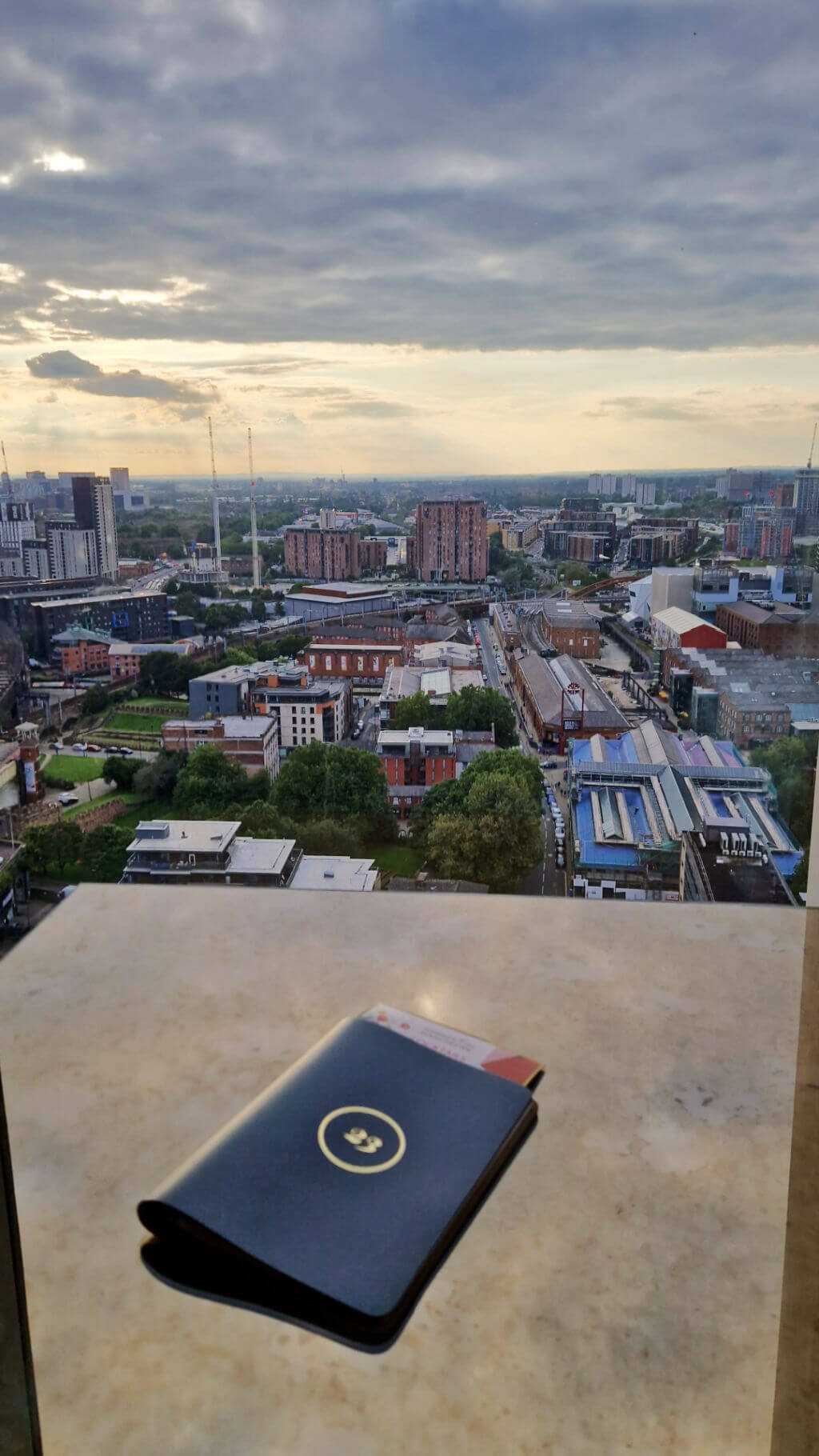 A view across Manchester from the cocktail bar of a tall hotel building.  There is a cocktail menu on the table