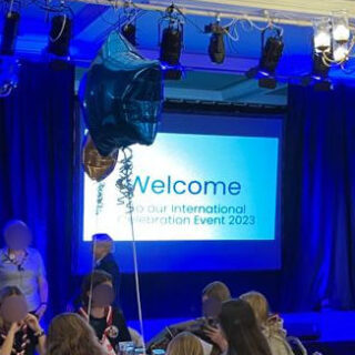 A stage lit up with blue lights and a screen with the word "Welcome" on it