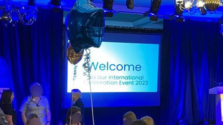 A stage lit up with blue lights and a screen with the word "Welcome" on it